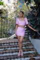 Woman in a pink sequin Filipiniana terno standing on outdoor steps with greenery in the background