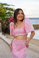 Woman wearing a pink sequin Filipiniana terno standing by a waterfront.