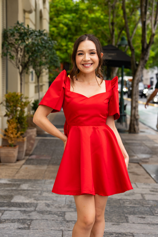 Filipina woman wearing  a red satin a-line mini dress with modern filipiniana sleeves to a celebration