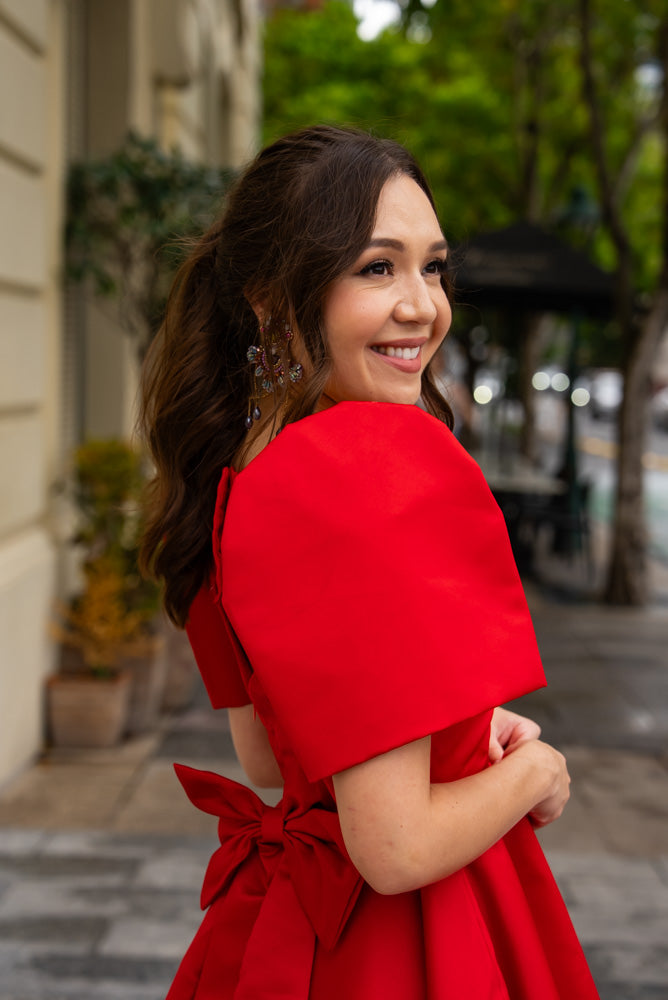 Woman wearing modern filipiniana dress in red duchess satin with traditional filipiniana sleeves
