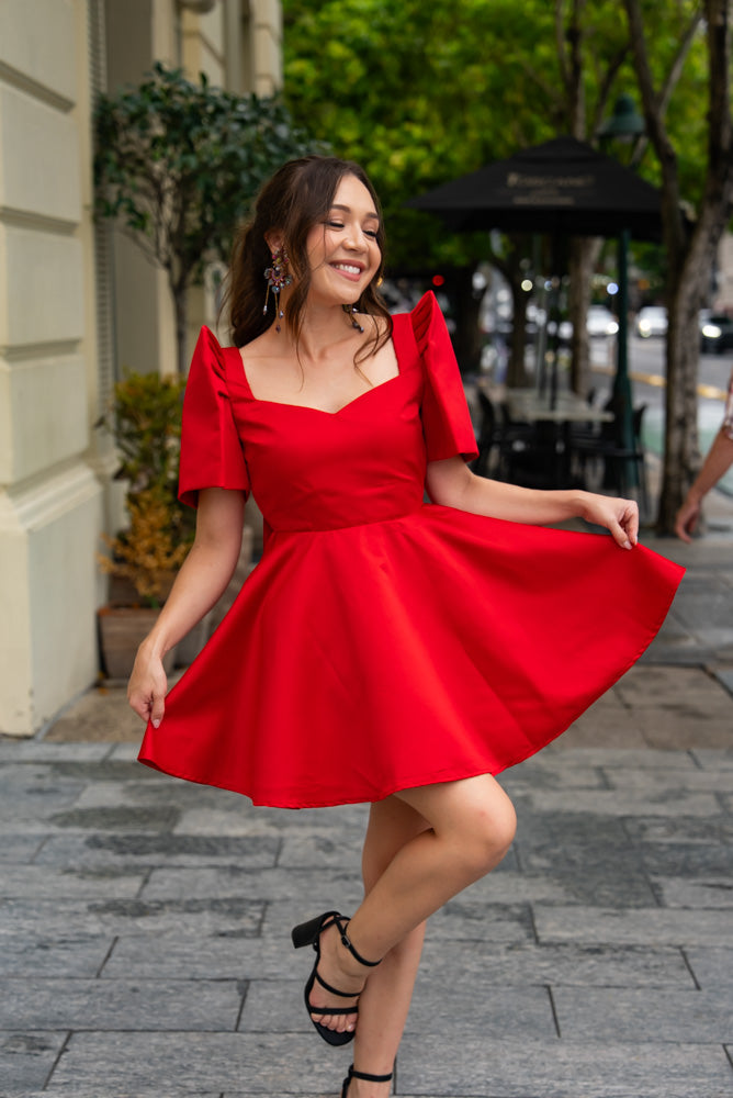 Half Filipina woman wearing red duchess satin Filipiniana mini dress with a line twirl worthy skirt and sweetheart neckline