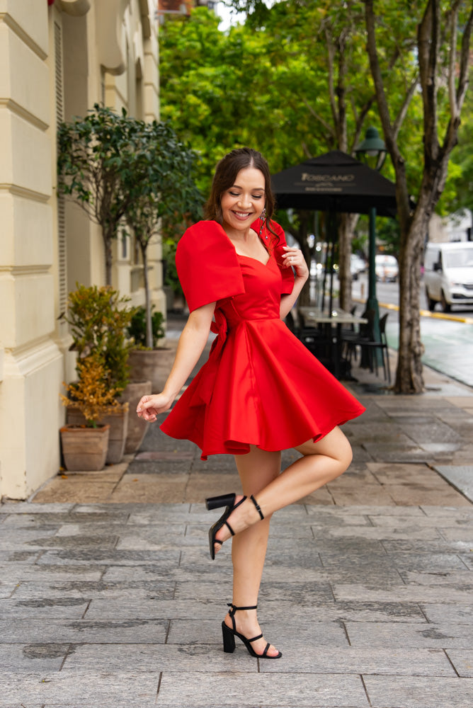 Filipina woman wearing red mini length filipiniana dress with backside decorative bow, a-line skirt, sweetheart neckline, and modern filipiniana butterfly sleeves