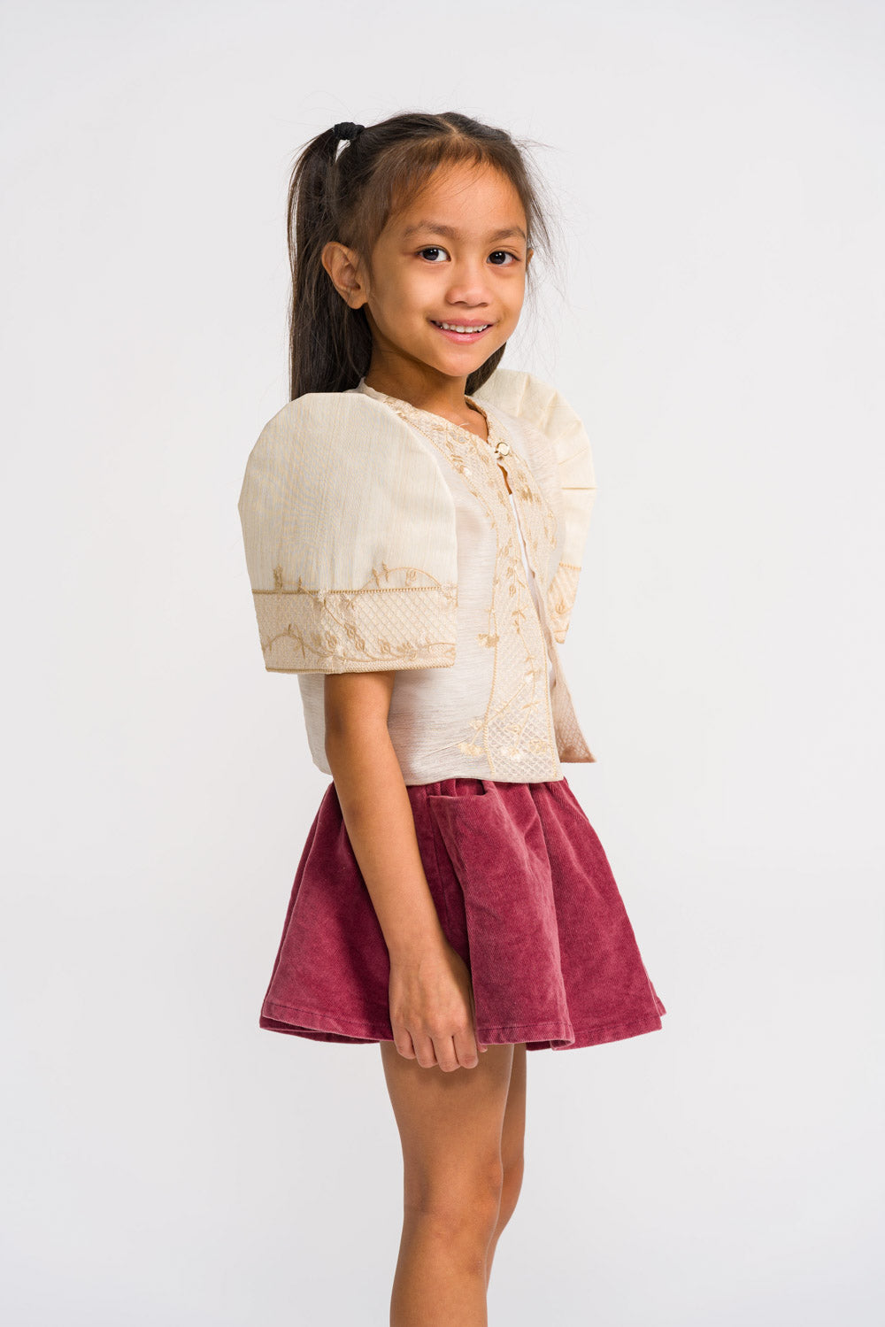 Side view of child wearing aiza filipiniana bolero with filipino butterfly sleeves made of cream jusilyn and gold embroidery